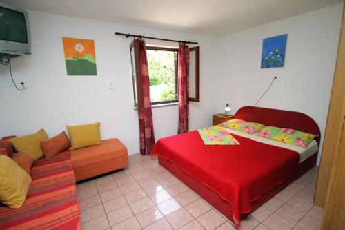 een slaapkamer met een rood bed en een bank bij Apartments by the sea Krk - 5400 in Krk