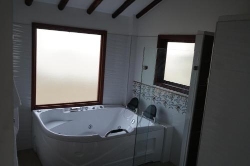 a white bath tub in a bathroom with two windows at Hotel Campestre Casa La María in Firavitoba