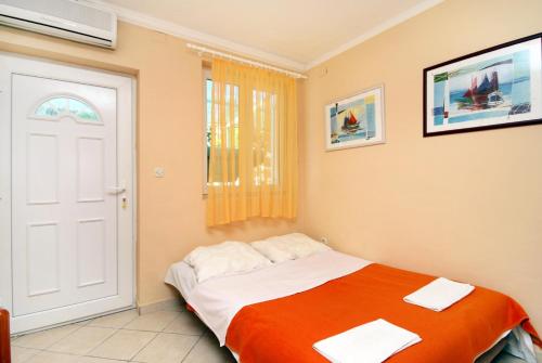 a bedroom with a bed with orange and white sheets at Studio Baska 5450b in Baška