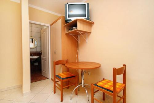 a room with a table and a tv on a wall at Studio Baska 5450b in Baška
