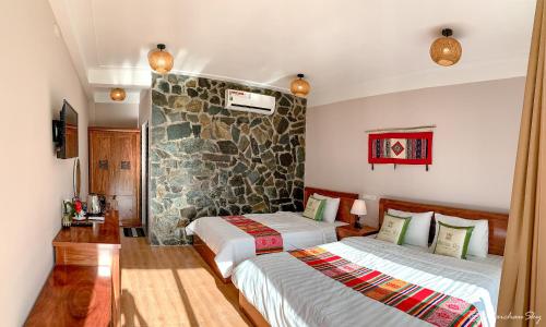 a bedroom with two beds and a stone wall at Mai Chau Sky Resort in Mai Chau