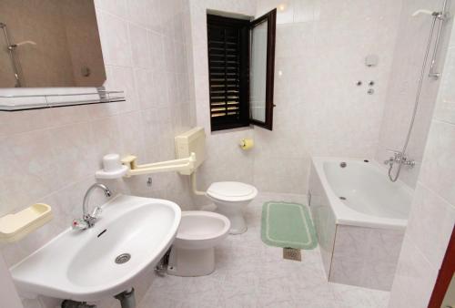 La salle de bains blanche est pourvue d'un lavabo, de toilettes et d'une baignoire. dans l'établissement Apartments with a parking space Krk - 5321, à Krk