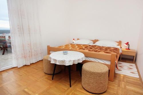 a bedroom with a bed and a table and a window at Apartments by the sea Vantacici, Krk - 5347 in Malinska