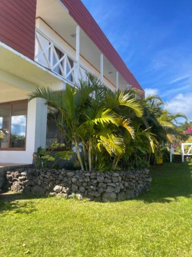 a house with palm trees in front of it at Teanehi Bed & Breakfast in Hanga Roa
