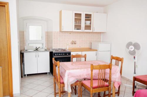 Apartments by the sea Punat, Krk - 5329 في بونات: مطبخ مع طاولة وكراسي وموقد