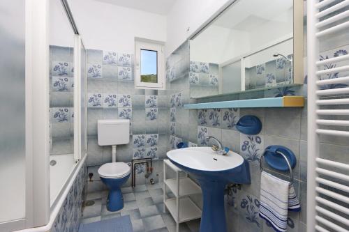 La salle de bains bleue et blanche est pourvue d'un lavabo et de toilettes. dans l'établissement Apartments with a parking space Punat, Krk - 5410, à Punat