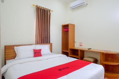een slaapkamer met een bed met een rode deken erop bij RedDoorz near Rita Supermall Purwokerto 2 in Purwokerto