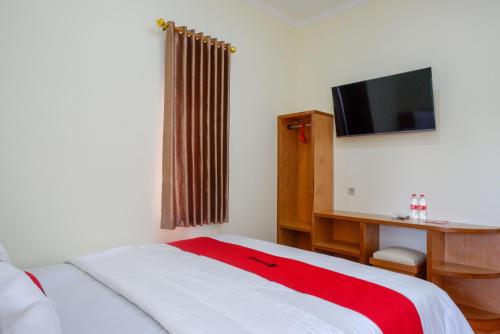 een slaapkamer met een bed, een bureau en een televisie bij RedDoorz near Rita Supermall Purwokerto 2 in Purwokerto