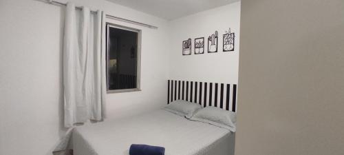 um pequeno quarto branco com uma cama e uma janela em Flat Home Practice em São Luís