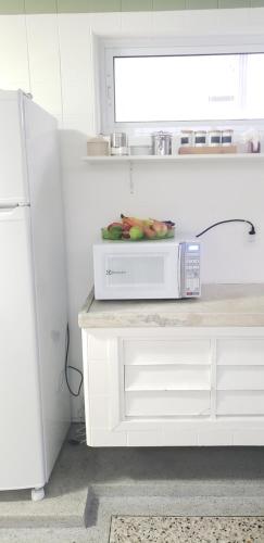 a white kitchen with a microwave on a counter at Jardim Secreto in Sao Paulo
