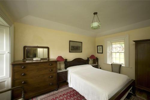 a bedroom with a bed and a dresser and a mirror at Salterbridge Gatelodge in Cappoquin