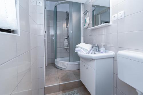 a white bathroom with a sink and a shower at Apartments by the sea Punat, Krk - 5351 in Punat