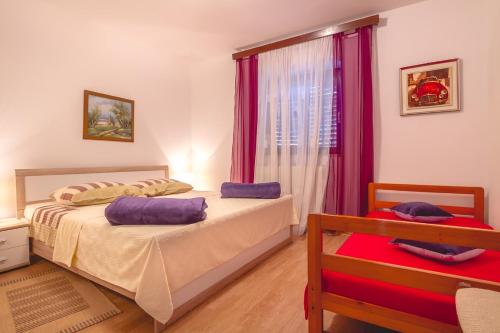 a bedroom with two beds and a window with purple curtains at Apartment Njivice 5362b in Njivice