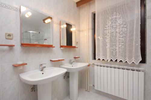 - une salle de bains blanche avec deux lavabos et un miroir dans l'établissement Apartments with a parking space Punat, Krk - 5375, à Punat