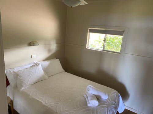 a small bedroom with a bed with a window at Lorsens on the River - Shoalhaven Heads in Shoalhaven Heads