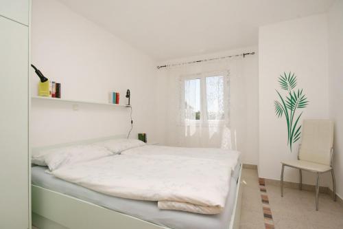 a white bedroom with a bed and a chair at Apartments with parking space Pinezici, Krk - 5464 in Pinezici