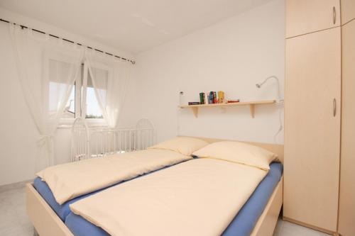 a bedroom with a bed with white walls and a window at Apartment Pinezici 5464d in Pinezici