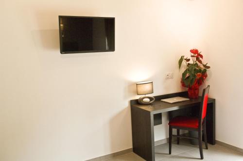 a desk with a red chair and a television on a wall at The Originals City, Hôtel Les Bastides du Gapeau in Solliès-Toucas