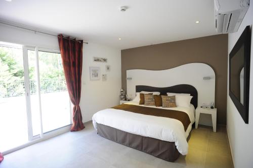a bedroom with a large bed and a large window at The Originals City, Hôtel Les Bastides du Gapeau in Solliès-Toucas