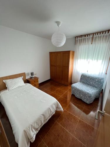 una camera con un letto bianco e una sedia di Apartamento Bouzavella Panxón a Nigrán