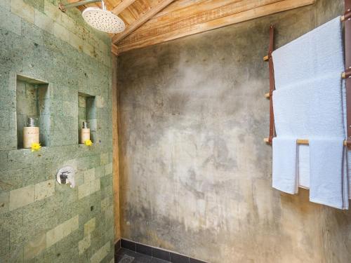 een badkamer met een douche en handdoeken aan de muur bij Wisnu Lumbung Uluwatu in Uluwatu
