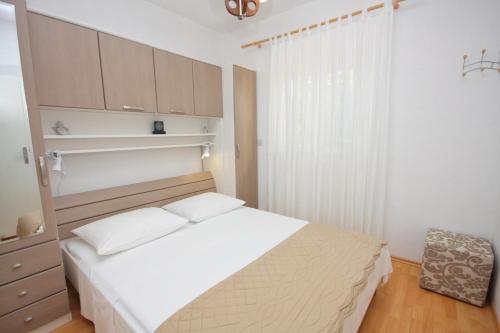1 dormitorio con cama blanca y ventana en Apartments with a parking space Supetar, Brac - 5385, en Supetar