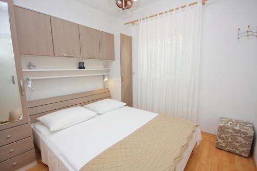 a bedroom with a white bed and a window at Apartments with a parking space Supetar, Brac - 5385 in Supetar