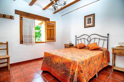 1 dormitorio con cama con sábanas de color naranja y ventana en Casa Rural La Herradura del río Júcar, en Jorquera