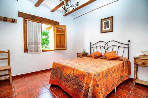 1 dormitorio con cama con sábanas de color naranja y ventana en Casa Rural La Herradura del Júcar, en Jorquera
