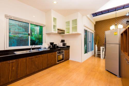 eine Küche mit Holzschränken und einem Kühlschrank aus Edelstahl in der Unterkunft Irawan House in Ao Nang Beach