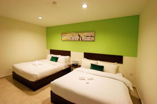 a room with two beds and a green wall at Golden Roof Hotel Falim Ipoh in Ipoh