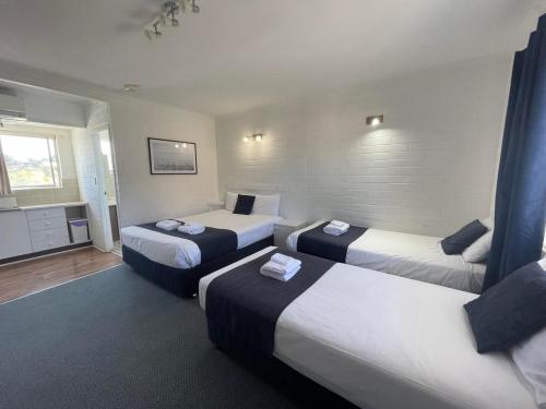 una camera d'albergo con tre letti e una televisione di Forster Motor Inn a Forster