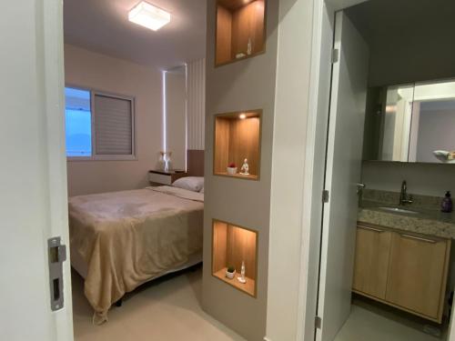 a small bedroom with a bed and a sink at Apartamento em Bertioga com varanda gourmet in Bertioga