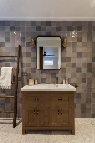 a bathroom with a sink and a mirror at Paradise Beach 3 Bedroom Luxury Accommodation in Papamoa