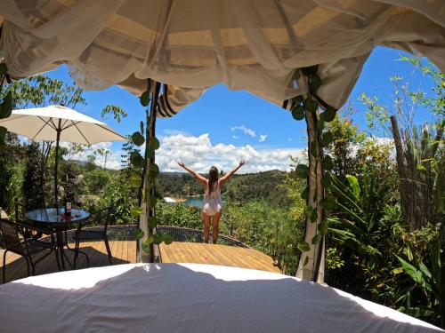 a woman standing on a porch with her arms in the air at Levit Glamping - Hotel Guatapé Peñol in Guatapé