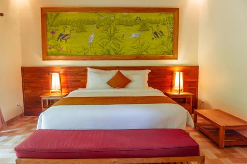 1 dormitorio con 1 cama y una pintura en la pared en Prayatna Villas en Ubud