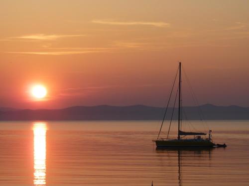 a sail boat in the water at sunset at Résidence Bona vue mer panoramique in Hyères
