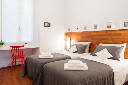 2 Betten in einem Zimmer mit einem roten Stuhl in der Unterkunft The Best Rent - Apartment near Porta Romana in Mailand