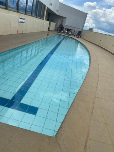 a swimming pool with blue tiles on the side of a building at Flat encantador com piscina e área de lazer in Brasilia