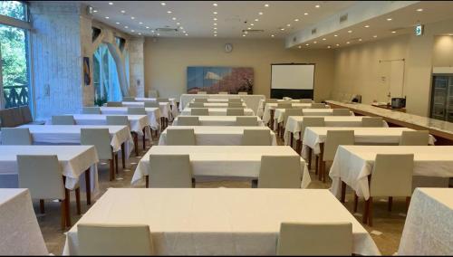a large room with white tables and chairs and a screen at Fujisan Garden Hotel in Yamanakako