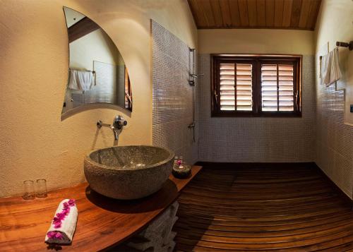 baño con lavabo de piedra grande y espejo en Hôtel **** Palissandre Côte Ouest, en Morondava