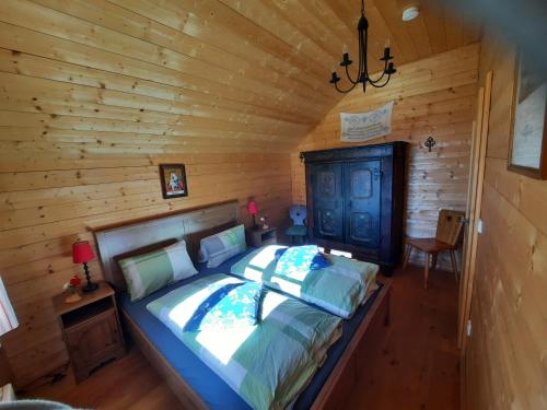 - une chambre avec un lit dans une cabane en rondins dans l'établissement Marhütte, à Ebene Reichenau
