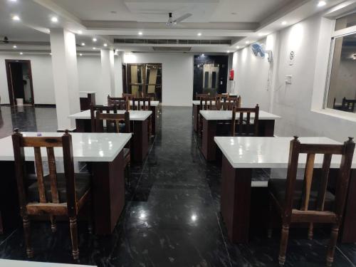 a restaurant with white tables and wooden chairs at Hotel Shree Krishna Palace in Rājgīr