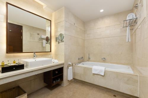 a bathroom with a tub and a sink and a mirror at Millennium Hotel Wuxi in Wuxi