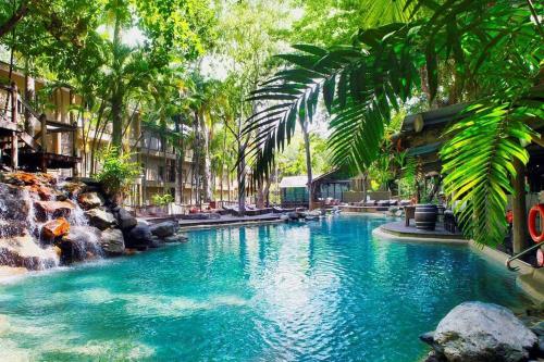 een zwembad met blauw water en palmbomen bij RAMADA RESORT - Stylish Hotel Studio Apartment in Port Douglas