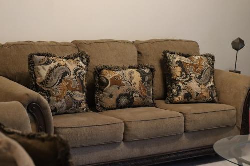 a brown couch with four pillows on it at Retreat by the Beach Lovely New 2 Bedroom in Discovery Bay
