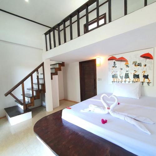 una camera da letto con un letto bianco con un nastro di Putra Boyan Cottages a Gili Trawangan