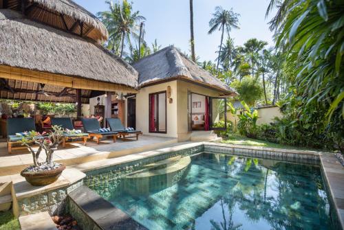 a villa with a swimming pool in front of a house at Alam Anda Ocean Front Resort & Spa CHSE Certified in Tejakula