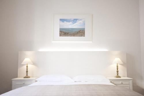 a bedroom with a white bed with two lamps at And So in Lecce