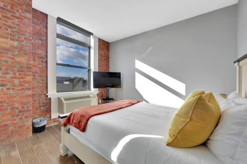 1 dormitorio con cama y pared de ladrillo en Elegant Main Street Living* Near NYC, en Hackensack